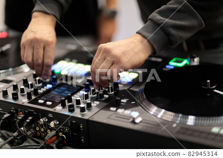 DJ mixes tracks on a professional MIDI controller 82945314