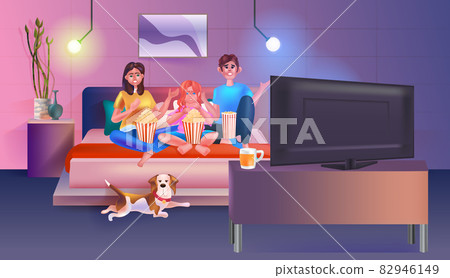 Family sitting on couch watching tv and eating popcorn happy parents and daughter spending time together Family sitting on couch watching tv and eating popcorn happy parents and daughter spending time together 82946149