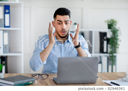 Stressed Arab businessman with laptop making mistake in work project, cannot meet deadline, feeling terrified in office Stressed Arab businessman with laptop making mistake in work project, cannot meet deadline, feeling terrified in office 82946361