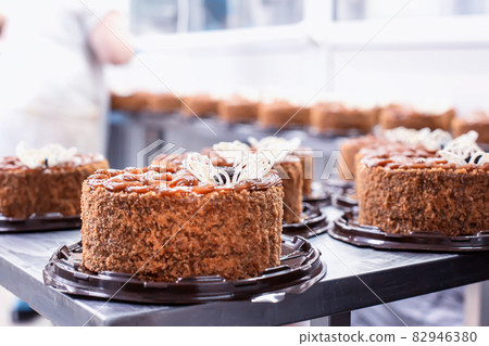 A lot of chocolate sponge cakes with condensed milk and prunes in the confectionery industry, making. Food industry, torte A lot of chocolate sponge cakes with condensed milk and prunes in the confectionery industry, making. Food industry, torte 82946380