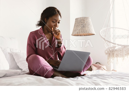 Sleepy African Freelancer Lady Using Laptop And Yawning In Bedroom Sleepy African Freelancer Lady Using Laptop And Yawning In Bedroom 82946383