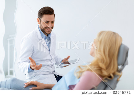 Cheerful man dentist having conversation with blonde woman patient 82946771