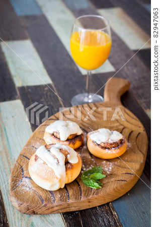Homemade buns with cinnamon and a glass of juice. High quality photo. 82947063
