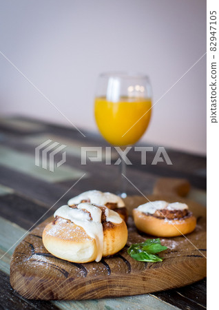 Homemade buns with cinnamon and a glass of juice. High quality photo. 82947105