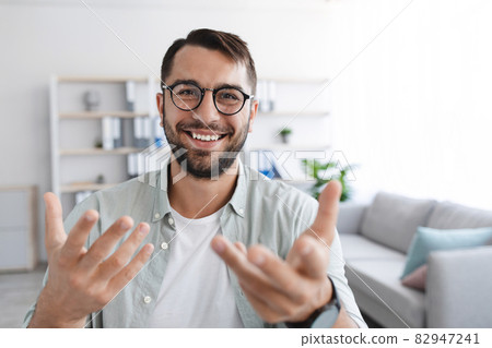 Smiling emotional adult european male with beard in glasses looks at camera and shooting video for blog Smiling emotional adult european male with beard in glasses looks at camera and shooting video for blog 82947241