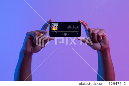 Black Male Hands Holding Smartphone With Opened Audio Player App Black Male Hands Holding Smartphone With Opened Audio Player App 82947242