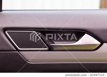 Modern car door trim with tweeter and door handle with metal insert, close-up Modern car door trim with tweeter and door handle with metal insert, close-up 82947310