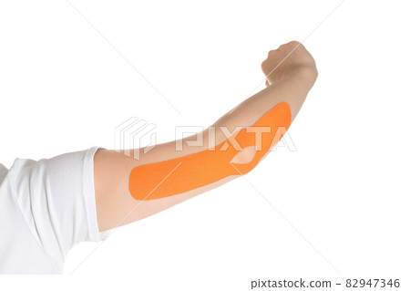 A woman's hand on which an orange kinesiological tape is glued to fix muscles and a joint. Alternative medicine, taping, isolate. Close-up 82947346
