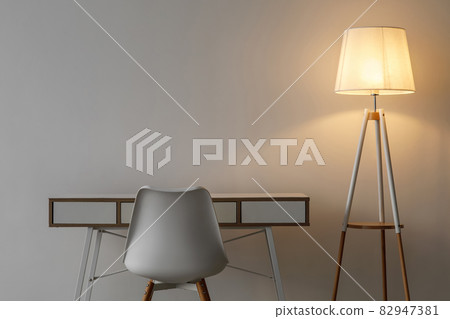 White vacant chair, table and glowing lamp in evening on gray wall background in office or living room 82947381