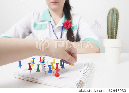 The children's doctor plays with the child arrange multi-colored buttons. The concept of the development of logic and thinking in children, education 82947980