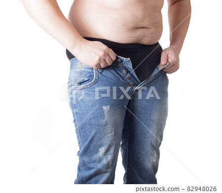 An obese man tries to put on tight little shorts on a white background. Overweight concept, wrong lifestyle An obese man tries to put on tight little shorts on a white background. Overweight concept, wrong lifestyle 82948026