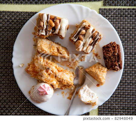 Leftovers in a plate on the table with sweets cakes, close-up 82948049