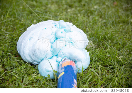 An exploded cylinder with construction foam on the grass. Balloon defect, close-up An exploded cylinder with construction foam on the grass. Balloon defect, close-up 82948058