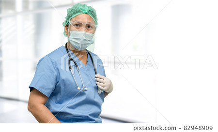 Asian doctor wearing face shield and PPE suit new normal to check patient protect safety infection Covid19 Coronavirus outbreak at quarantine hospital with copy space. 82948909