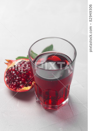Jug of pomegranate juice with pieces of pomegranate fruits on a white background Jug of pomegranate juice with pieces of pomegranate fruits on a white background 82949306