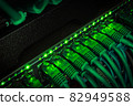 Close up of green network cables from data center connected with patch cord to black switch glowing in the dark 82949588