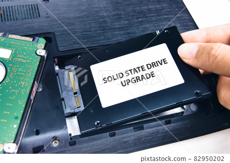 A technician installs a Solid State Drive (SSD) in a laptop computer 82950202
