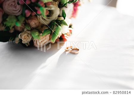 Beautiful toned picture with wedding rings against the background of a bouquet of flowers 82950814