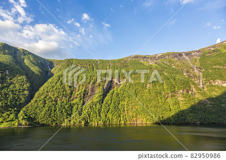 Impression from cruise ship on the way through Geiranger fjord in Norway at sunrise in summer Impression from cruise ship on the way through Geiranger fjord in Norway at sunrise in summer 82950986