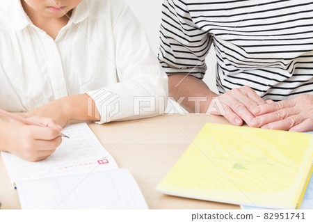 A child studying and a grandmother watching over A child studying and a grandmother watching over 82951741