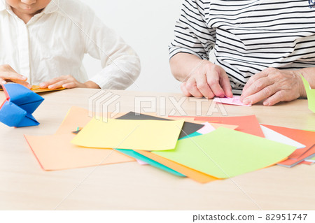 Children and grandmother playing with origami 82951747