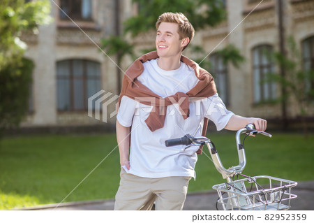 A smiling young man in a ehite tshirt on a bike A smiling young man in a ehite tshirt on a bike 82952359