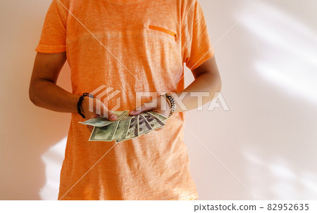 A young tanned man holds money dollars in his hands. Space for copying text A young tanned man holds money dollars in his hands. Space for copying text 82952635