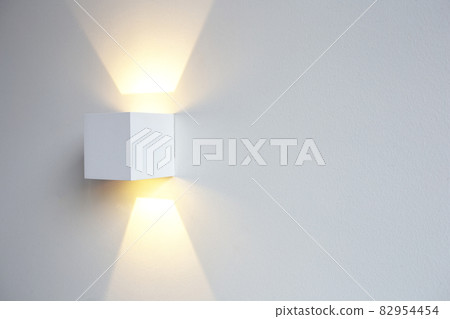 A glowing modern aluminum led lamp on white wall in retro home decoration with copy space. Luxury design A glowing modern aluminum led lamp on white wall in retro home decoration with copy space. Luxury design 82954454