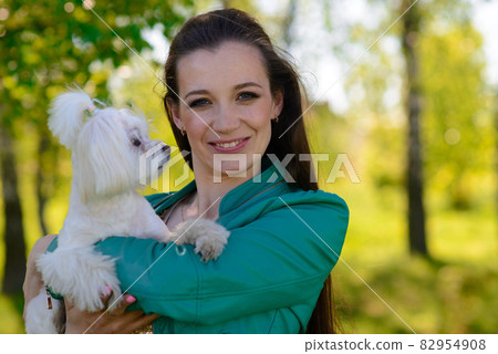 Young girl with her dog. Puppy white dog is running with it's owner. Concept about friendship, animal and freedom. Young girl with her dog. Puppy white dog is running with it's owner. Concept about friendship, animal and freedom. 82954908