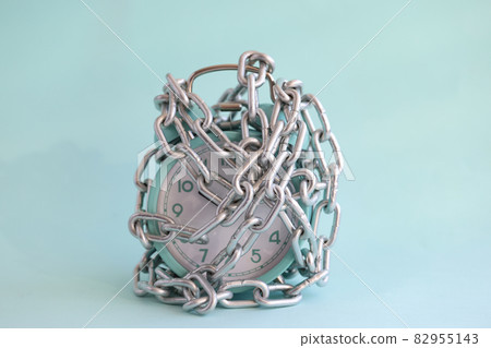 Turquoise alarm clock is wrapped in chrome chain closeup 82955143