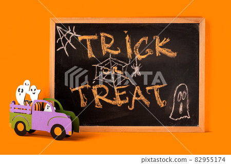 Happy halloween holiday concept. Halloween handmade decorations, ghosts in car, spider, trick or treat text on black chalk board frame on orange background. Halloween festival, greeting card. Happy halloween holiday concept. Halloween handmade decorations, ghosts in car, spider, trick or treat text on black chalk board frame on orange background. Halloween festival, greeting card. 82955174