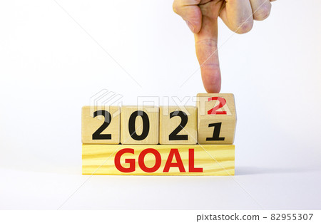 Planning 2022 goal new year symbol. Businessman turns a wooden cube and changes words 'Goal 2021' to 'Goal 2022'. Beautiful white background, copy space. Business, 2022 goal new year concept. Planning 2022 goal new year symbol. Businessman turns a wooden cube and changes words 'Goal 2021' to 'Goal 2022'. Beautiful white background, copy space. Business, 2022 goal new year concept. 82955307