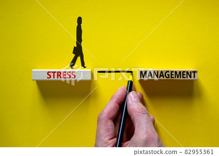 Stress management symbol. Wooden blocks with words 'Stress management'. Yellow background. Businessman hand, businesswoman icon. Psychological, business and stress management concept. Copy space. 82955361