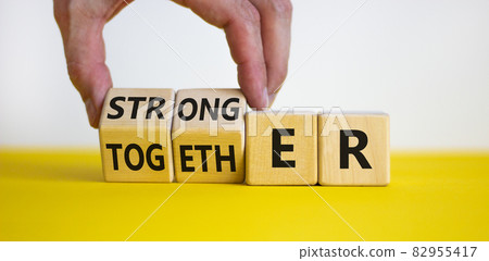 Stronger together symbol. Businessman turns cubes and changes the word together to stronger. Beautiful yellow table, white background, copy space. Business, motivational and stronger together concept. Stronger together symbol. Businessman turns cubes and changes the word together to stronger. Beautiful yellow table, white background, copy space. Business, motivational and stronger together concept. 82955417