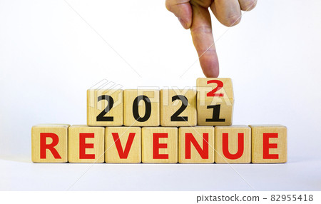 Symbol of planning 2022 revenue new year. Businessman turns a wooden cube and changes words 'revenue 2021' to 'revenue 2022'. Beautiful white background, copy space. Business, 2022 revenue concept. 82955418
