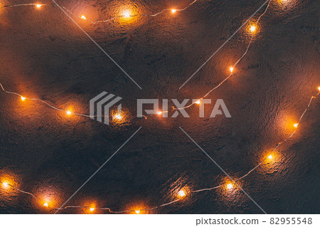Warm light illuminated garland close up on dark background Warm light illuminated garland close up on dark background 82955548