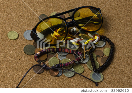 sun glasses with various bracelets and coins rest casually on the light brown skin 82962610