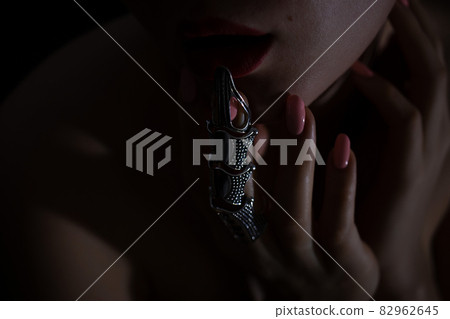 Gothic style shot of a woman with claw rings touching lips 82962645