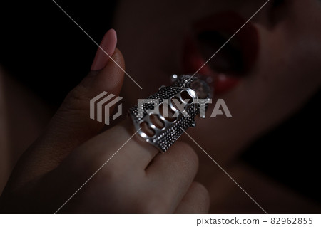 Gothic style shot of a woman with claw rings touching lips 82962855