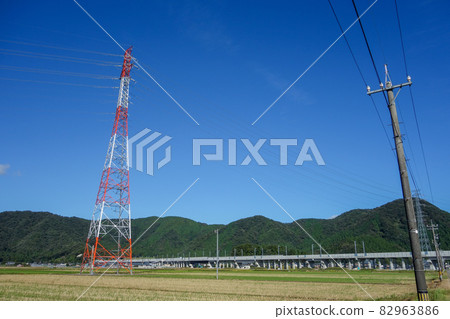 Red and white steel tower blue sky mountain countryside 82963886
