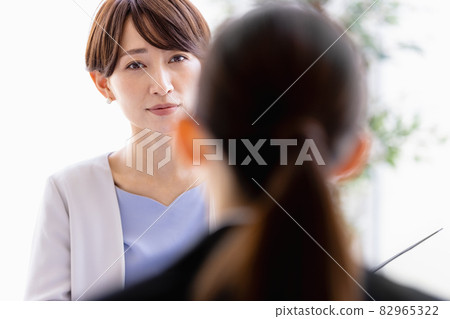 中年婦女與一位身著西裝的女士面對面坐著交談 中年婦女與一位身著西裝的女士面對面坐著交談 82965322