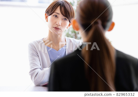 Middle-aged woman talking to a woman in a suit sitting face to face Middle-aged woman talking to a woman in a suit sitting face to face 82965332
