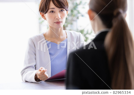 Middle-aged woman talking to a woman in a suit sitting face to face Middle-aged woman talking to a woman in a suit sitting face to face 82965334