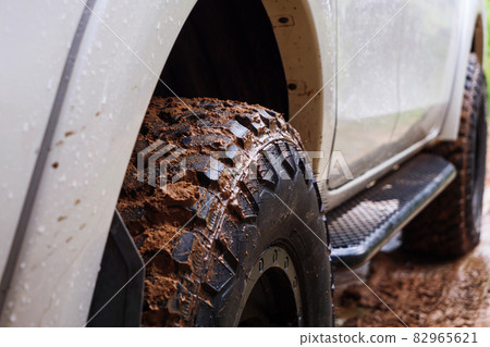 Dirty rear wheel of the off-road 4x4 truck at a countryside rural place in Rainy vibe, 4wd vehicle in rain, Selective focus shallow depth of field 82965621