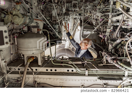 Pilot looking at the technical condition of the aircraft in the hangar Pilot looking at the technical condition of the aircraft in the hangar 82966421