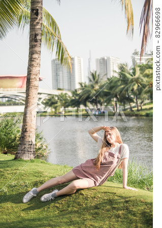 Pretty girl in casual clothing sitting the grass in the park. Long blond hair. Trendy casual summer or spring outfit 82966698