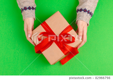 Woman hands holding gift box on green background Woman hands holding gift box on green background 82966798