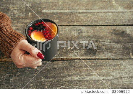 Woman's hands in warm sweater holding a cup of mulled wine Woman's hands in warm sweater holding a cup of mulled wine 82966933