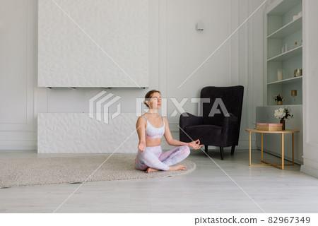 View of beautiful young woman working out in luxury fitness center, doing yoga or pilates exercise. 82967349