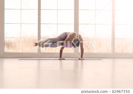 View of beautiful young woman working out in luxury fitness center, doing yoga or pilates exercise. 82967350